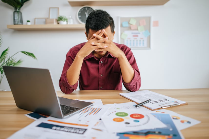 man-working-with-laptop-paperwork-with-stress